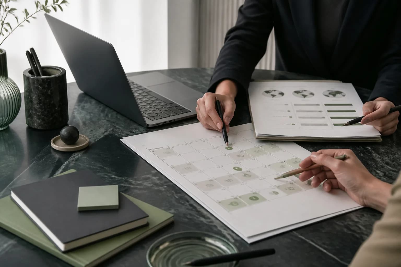 A legal team reviewing trademark deadlines on a calendar beside a laptop and printed portfolio lists